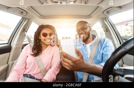 Happy black man and woman driving car and using smartphone Stock Photo