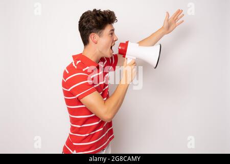 Handsome young man over isolated white background shouting through a megaphone Stock Photo