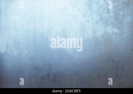 Blurred village landscape with a house and trees behind dirty glass. Abstract art photography. Stock Photo