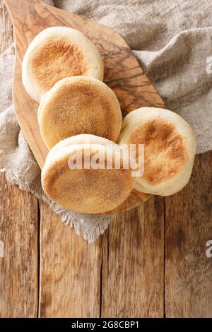 Freshly baked English muffins close-up in a board on the table. vertical top view from above Stock Photo