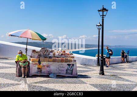 Nazare, Portugal - June 28, 2021: Woman in traditional clothing selling dried fruits on the Miradouro do Suberco  Stock Photo