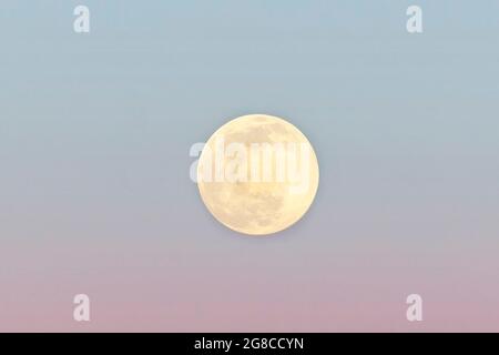 Full moon on sunset sky, close-up. Pink and blue, dreamlike moon. Stock Photo