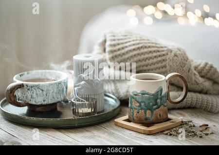 Cozy composition with ceramic cups and candles on a blurred background with bokeh. Stock Photo