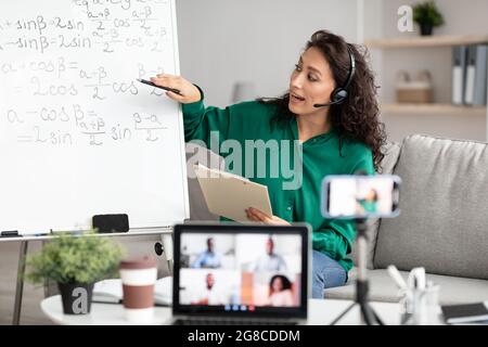 Female teacher in headset explaining trigonometric functions to students online Stock Photo