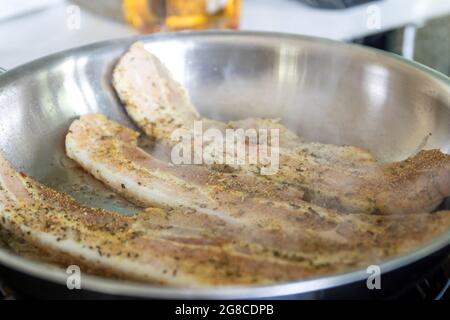 Frying bacon in stainless steel frying pan on stove top Stock Photo - Alamy