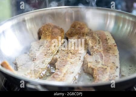 Frying bacon in stainless steel frying pan on stove top Stock Photo - Alamy