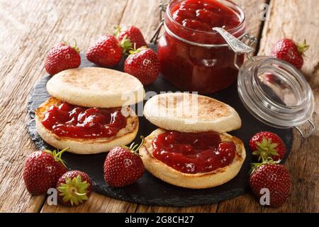 Delicious classic English muffins with strawberry jam close-up on a slate board on the table. horizontal Stock Photo
