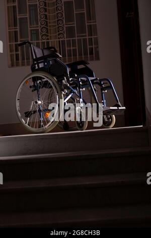 Wheelchair at the top of a flight of stairs Stock Photo