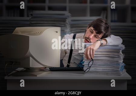 Tired exhausted man is sleeping at workplace at night. Overwork concept. Stock Photo