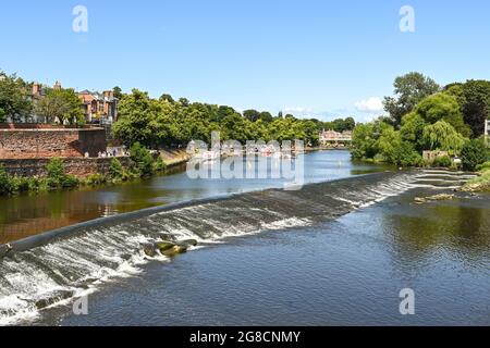 Chester, England - July 2021: Scenic view of boats on the River Dee, which flows through the city. In the foreground is a weir and fish pass. Stock Photo