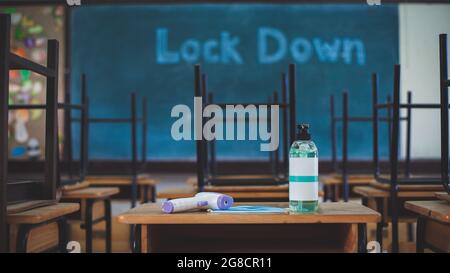 A bottle of hand sanitizer, digital thermometer and face mask standing on a table in  classroom at a school.School closed due to COVID-19 outbreak and Stock Photo