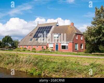 Farmhouse with 18 solar panels on roof by Dokkumer Ee canal in Friesland, Netherlands Stock Photo