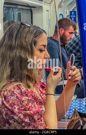 London, UK. 14th July, 2021. Applying make-up or just a refusal to follow the rules on masking - The underground is not much busier as, so called, 'Freedom Day' approaches. Credit: Guy Bell/Alamy Live News Stock Photo