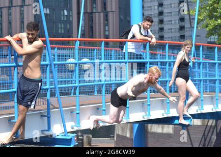 Salford, Greater Manchester, UK. 19th July 2021. Teenage swimmer dies at Salford Quays. Emergency Services recovered the body of a 19-year-old man from the water at Salford Quays, Salford, Greater Manchester, UK, on 18th July, 2021, at 7.40pm. During that day many swimmers were diving into the water. Man dives in at Salford Quays, 19th July, 2021. The man who died in the water at Salford Quays has been named as Ngapee Merenga. Credit: Terry Waller/Alamy Live News Stock Photo