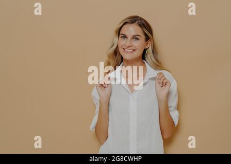 Young happy good looking woman with blond dyed hair in white shirt smiling cheerfully Stock Photo