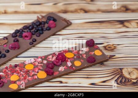 different kinds of chocolate with dried fruits on a wooden board Stock Photo