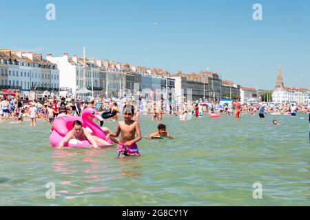 Crowdy beach in Weymouth. Tourists enjoy hot weather Stock Photo