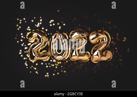 2022 year gold balloons on ribbons with confetti on pink wall. Happy New year 2022 eve