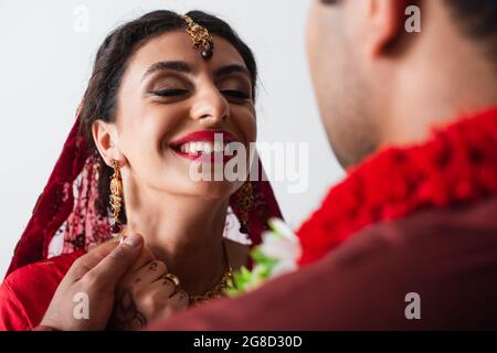 happy indian bride in headscarf holding hands with blurred bridegroom isolated on white Stock Photo