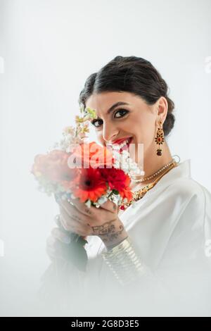 happy indian bride with mehndi holding bouquet of flowers on white Stock Photo