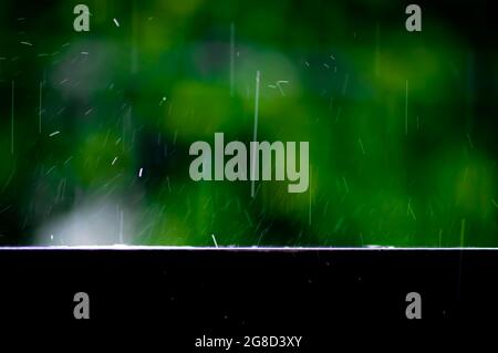 trails of falling raindrops on the edge of a fence with a long exposure, abstract background Stock Photo