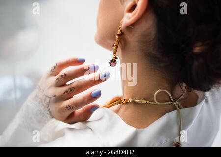 back view of young indian bride in earring wearing necklace on white Stock Photo