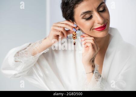 smiling indian bride wearing earring on white Stock Photo