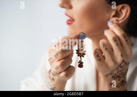 cropped view of blurred indian bride wearing earring while getting ready for wedding isolated on white Stock Photo