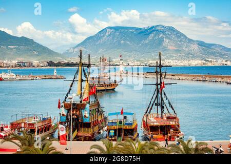 ALANYA, TURKEY - May 17, 2014: Touristic pirate tour boats in the sea, people wandering around at the Alanya Port in summer. Stock Photo