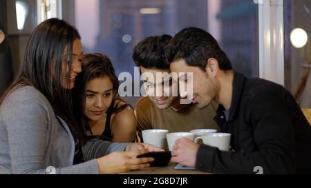 Young Indian friends sitting at a table with tea and having a discussion Stock Photo