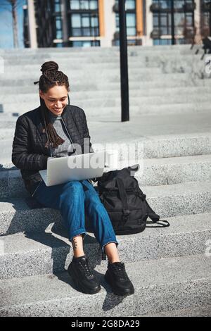 Joyful female freelancer working on her laptop outdoors Stock Photo