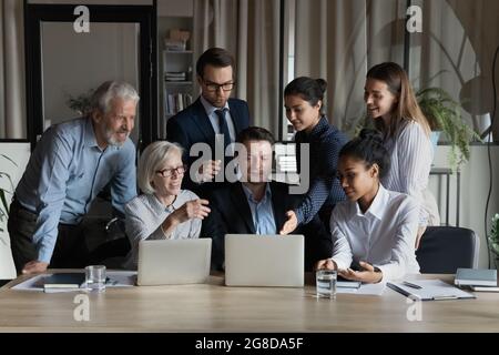 Engaged diverse business team looking, pointing at laptop screen Stock Photo