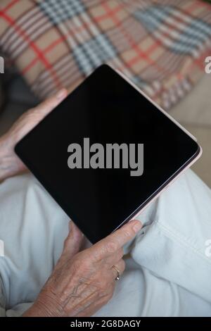 Hands of an senior woman holding blank screen tablet. Close up. Copy space, mockup. Stock Photo