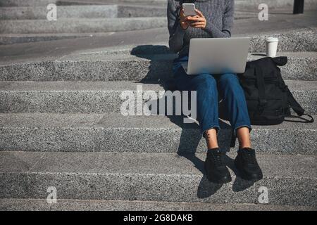 Woman with cornrows typing a text message on her cellular phone Stock Photo