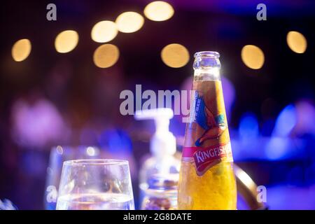 famous indian beer brand kingfisher bottle with bubble coming out with out of focus background lights with bokeh balls showing it placed in a bar club Stock Photo