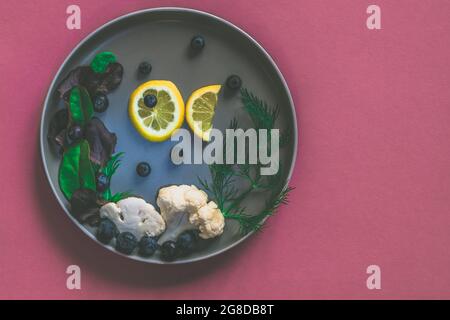 fish from lemon slices and sea from couliflower and blueberries on plate, copy space isolated Stock Photo