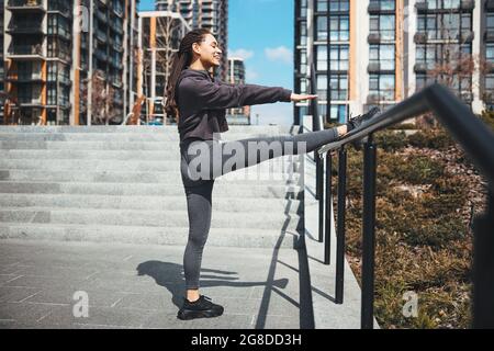 Pretty lady performing a stretching exercise using the handrail Stock Photo