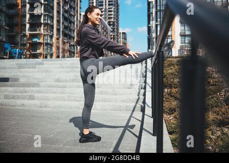 Sportswoman performing a leg stretching exercise outdoors Stock Photo