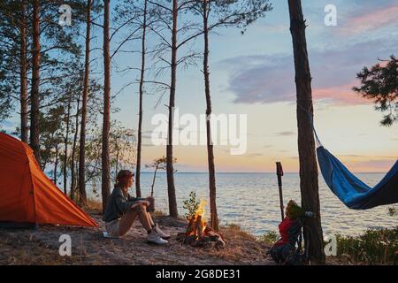 Backpacker warming up near campfire with tea Stock Photo