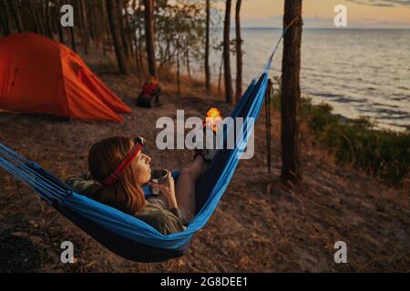 Lady laying in a hammock with metal teacup Stock Photo