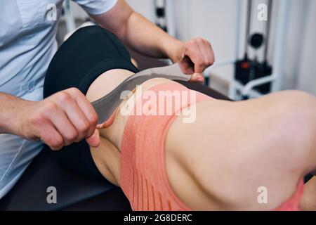 Male chiropractor is treating woman abdominal muscles Stock Photo