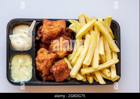 Dutch street food, portion of french fried potatoes, pieces of fried in oil cod fish fillet and two sauces close up Stock Photo