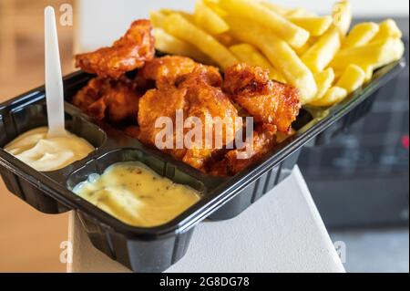 Dutch street food, portion of french fried potatoes, pieces of fried in oil cod fish fillet and two sauces close up Stock Photo