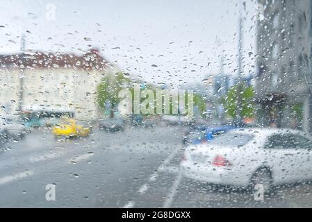 Car Driving In A Rain Storm With Blurred city view. View from car at raining day Stock Photo