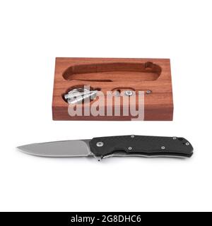 Modern folding knife unfolded on a white background along with a box with accessories. Knife with a folding blade. Stock Photo