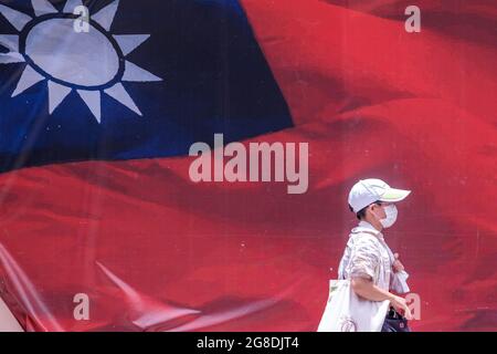 Taipei, Taiwan. 19th July, 2021. A man wearing a face mask walks past a Taiwanese flag ahead of the COVID-19 alert Level 3 restriction lift in Taipei. (Credit Image: © Walid Berrazeg/SOPA Images via ZUMA Press Wire) Stock Photo