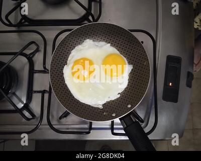 salvador, bahia, brazil - july 18, 2021: Fried eggs are seen in a frying pan on a stove in the kitchen of a house in Salvador city. Stock Photo