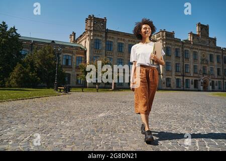 Mirthful young lady returning from the university Stock Photo