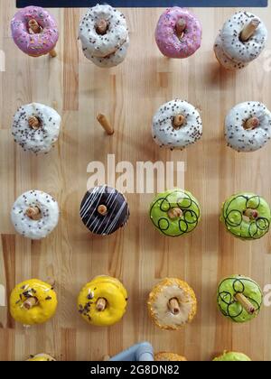 variety of different donuts hanging up on pegs on a wall at pastry shop Stock Photo