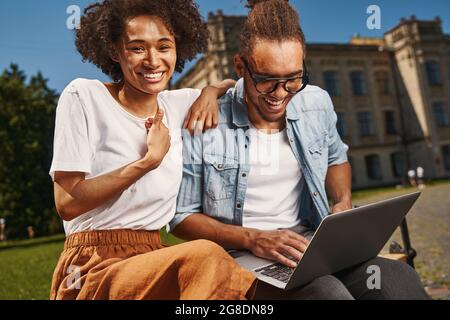 Delighted young couple using modern gadget outdoors Stock Photo